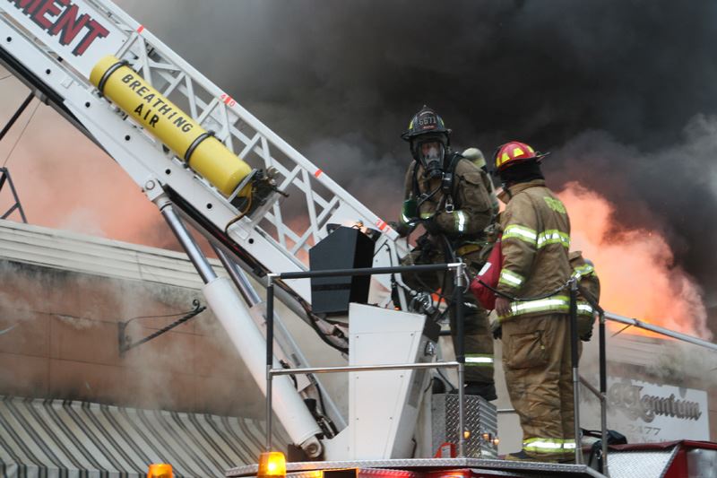 Fire fighter wearing a mask prepares to climb the ladder