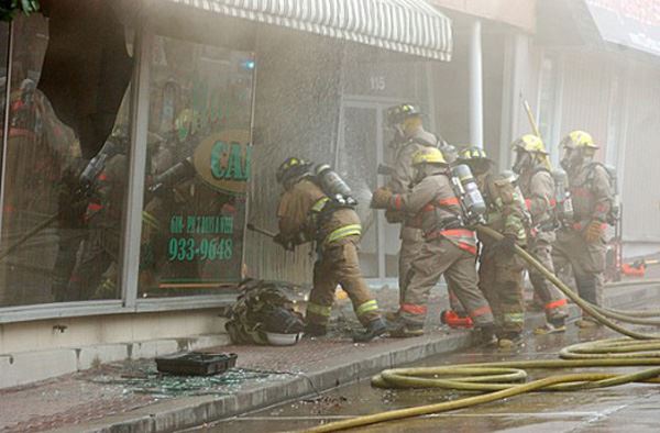 Group of fire fighters spraying a building through the windows