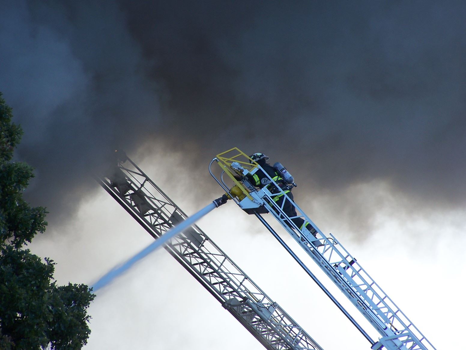 Fire fighter on a ladder spraying a fire