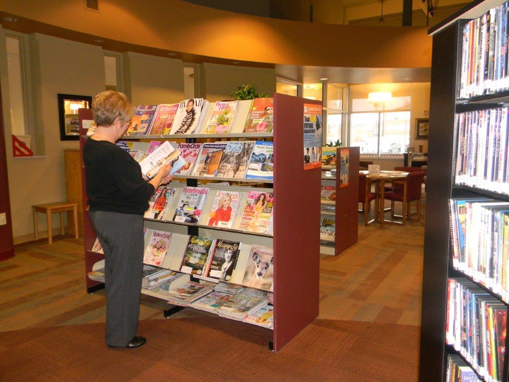 Woman reading a magazine by the magazine rack