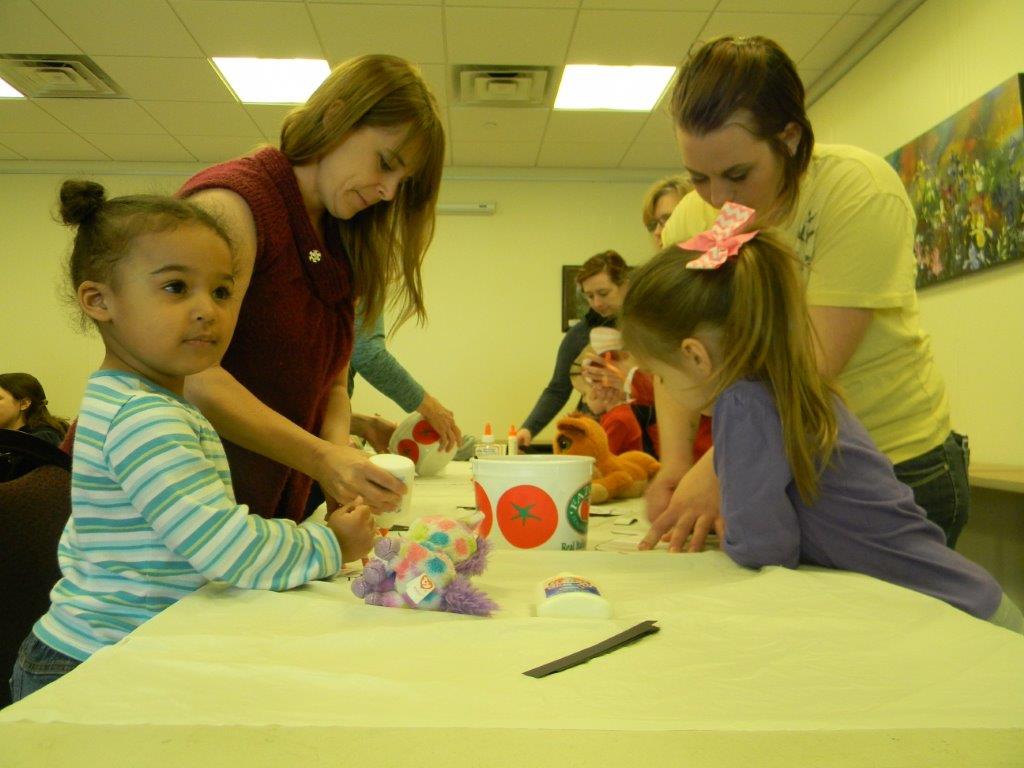 Adults helping small children create crafts